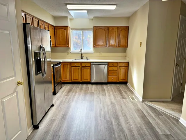 a kitchen with a refrigerator wooden floor a sink and a large window