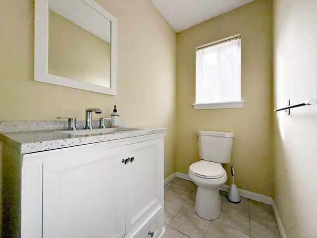 a bathroom with a granite countertop toilet sink and mirror