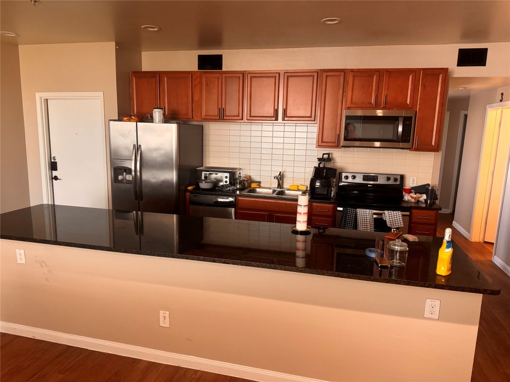 a kitchen with stainless steel appliances a refrigerator a stove a sink a refrigerator white cabinets and wooden floor