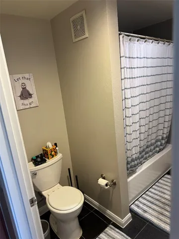 a bathroom with a toilet and a shower curtain
