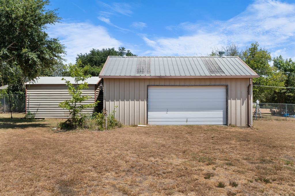 162 Warren Road Lorena, TX 76655 - Photo 31 of 39 Detached garage with metal siding and a roll-up door, complemented by an additional storage structure featuring horizontal siding