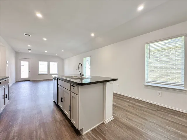 a kitchen with stainless steel appliances granite countertop a sink a stove and a wooden floors