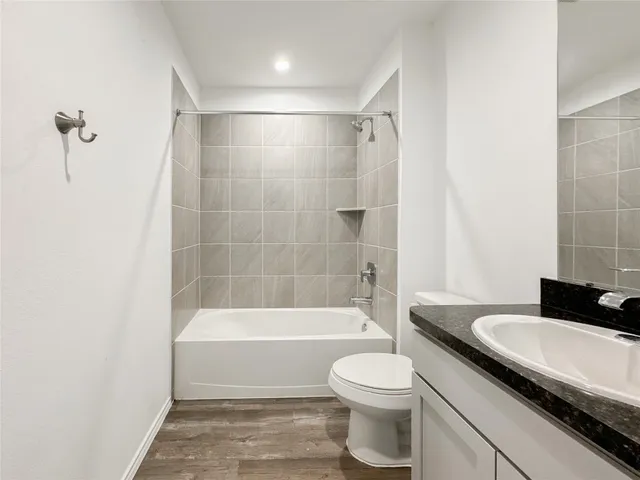 a bathroom with a granite countertop bathtub shower sink vanity and toilet