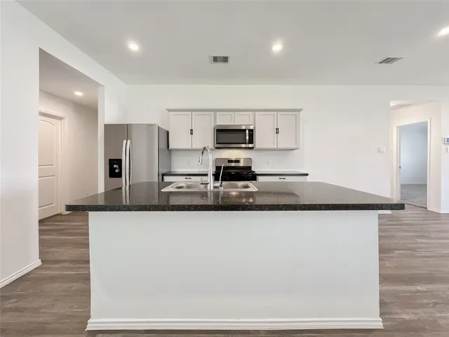 a large kitchen with stainless steel appliances granite countertop a sink a stove and a refrigerator