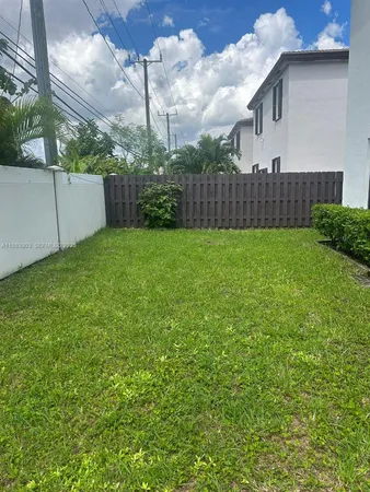 a view of a backyard with plants and wooden fence