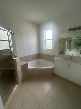 a spacious bathroom with a tub a sink and a large mirror