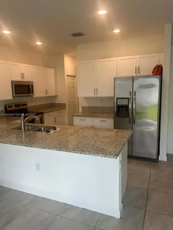 a kitchen with stainless steel appliances granite countertop a sink and a refrigerator