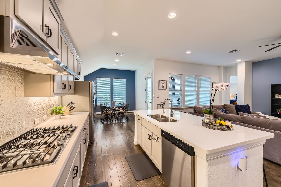 1332 Modoc Way Kyle, TX 78640 - Photo 28 of 28 Kitchen featuring under cabinet range hood, stainless steel appliances, open floor plan, an island with sink, and light countertops