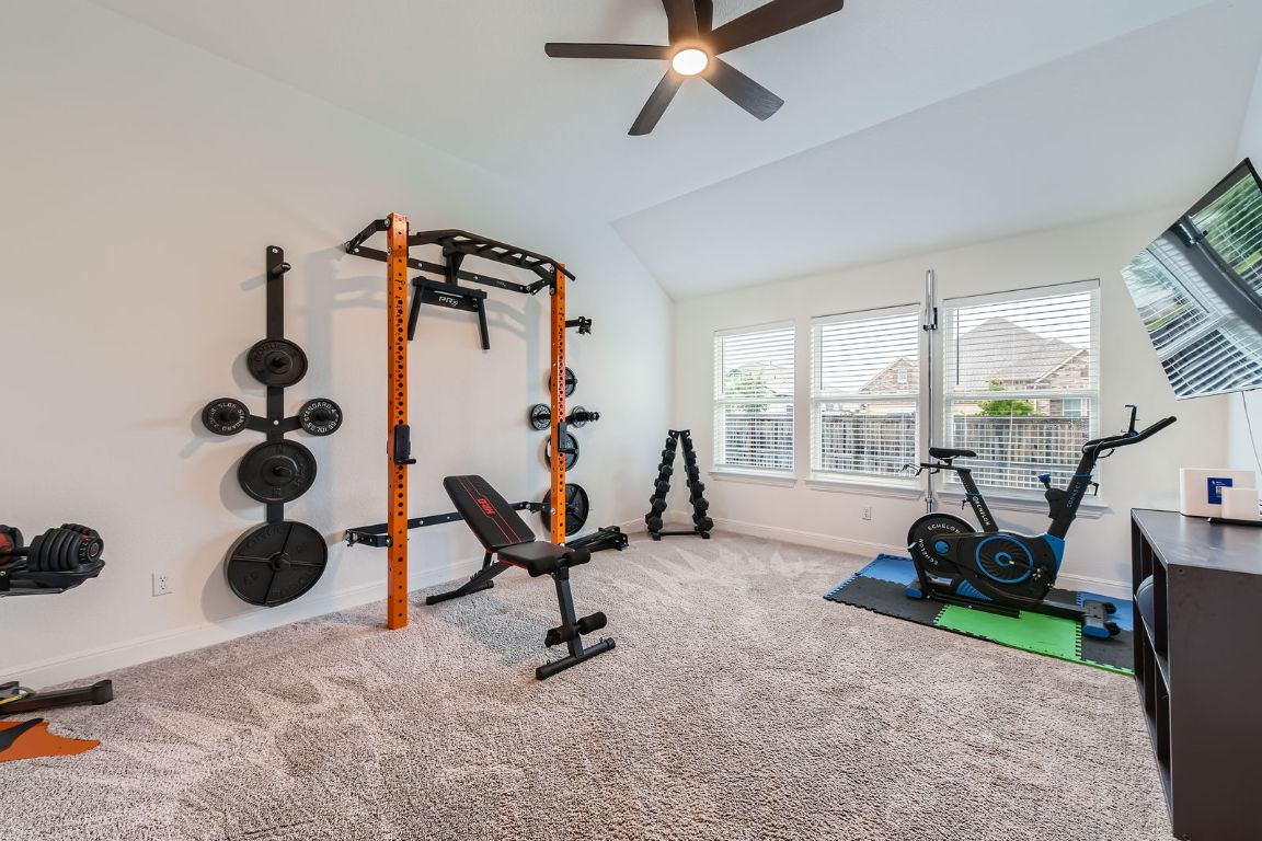 1332 Modoc Way Kyle, TX 78640 - Photo 25 of 28 Exercise area featuring a ceiling fan, vaulted ceiling, and carpet