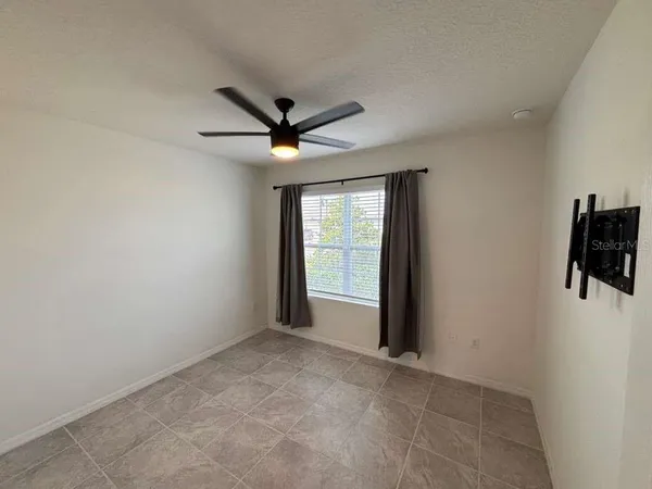 an empty room with window and a ceiling fan