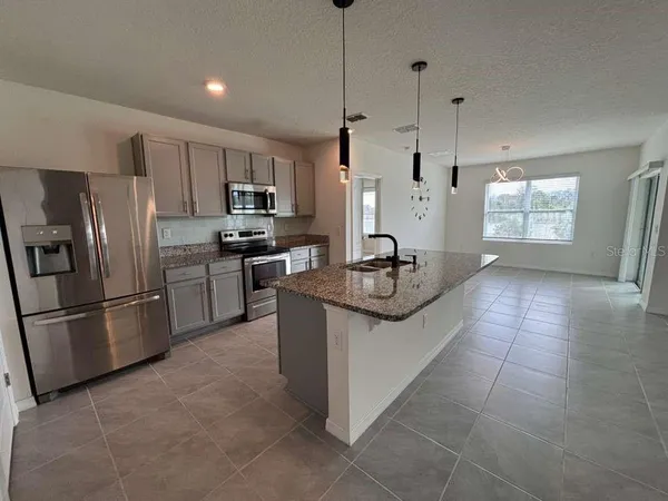 a kitchen with stainless steel appliances granite countertop a refrigerator a stove a sink and a refrigerator