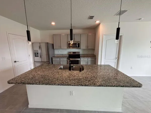 a kitchen with stainless steel appliances granite countertop a sink a refrigerator and a granite counter tops