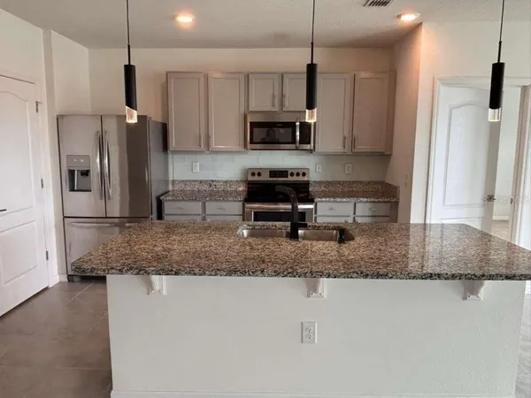 a kitchen with stainless steel appliances granite countertop a sink a stove and a refrigerator