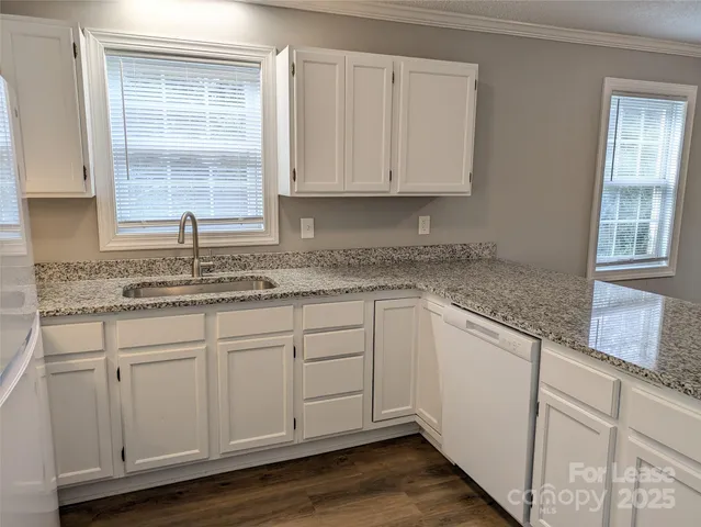 a kitchen with granite countertop white cabinets white appliances and a sink