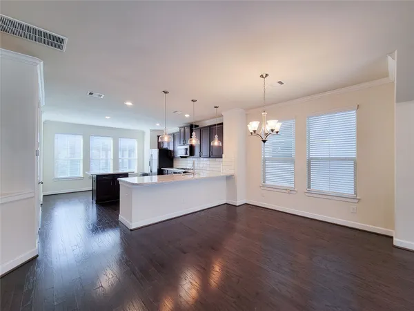 an open kitchen with white cabinets furniture and wooden floor