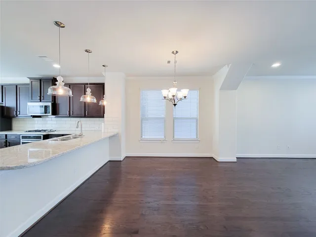 a large kitchen with granite countertop a large counter top a sink stainless steel appliances and cabinets