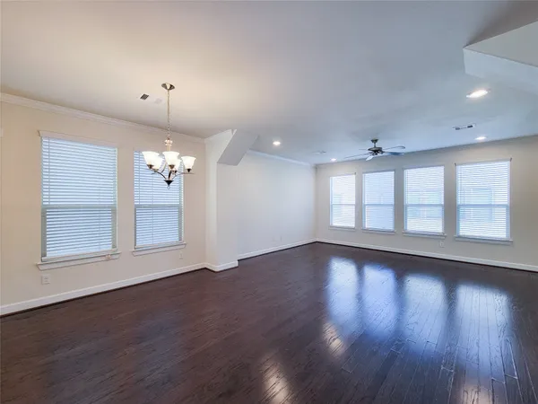 an empty room with wooden floor and large windows