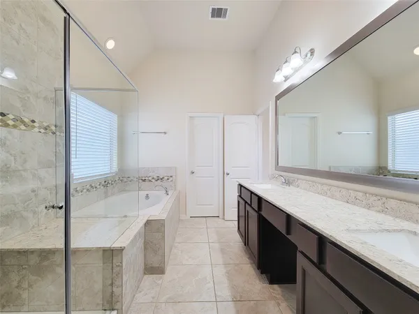 a spacious bathroom with a granite countertop sink a large mirror and a bathtub