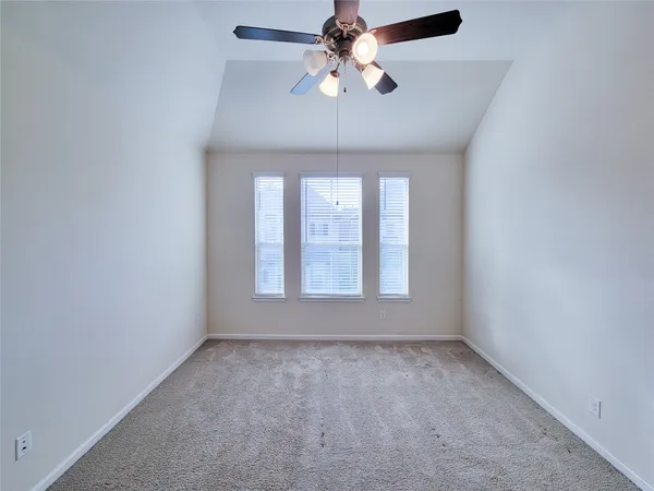 an empty room with a chandelier fan and windows
