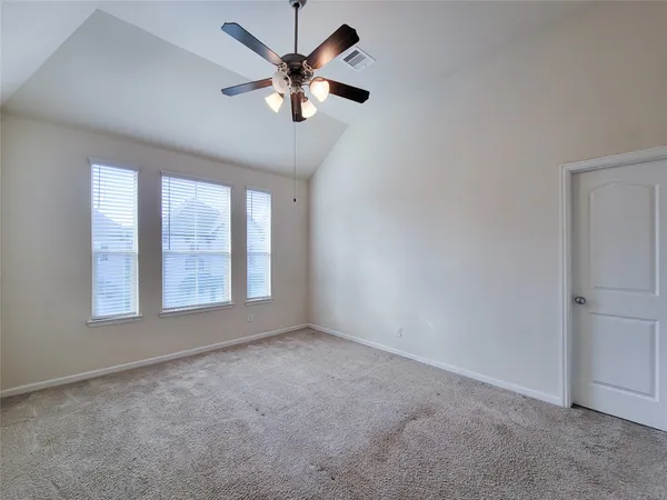 an empty room with chandelier fan and windows