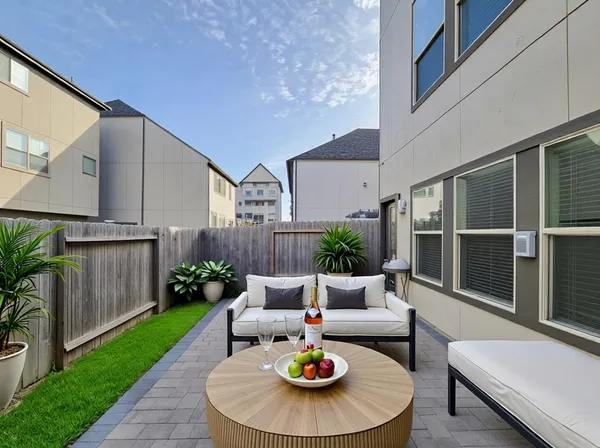 a view of a patio with couches table and chairs potted plants and wooden fence