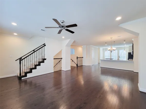 a view of an empty room with wooden floor and a ceiling fan