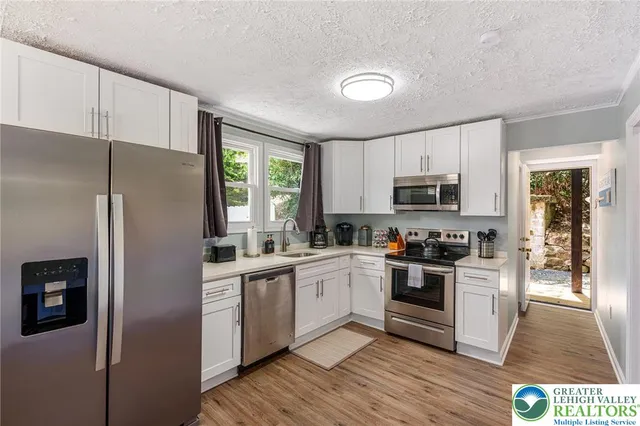 a kitchen with a refrigerator a sink and wooden floor