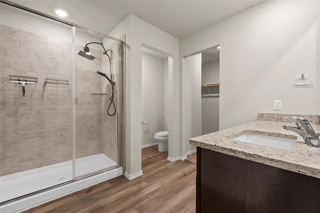a bathroom with a granite countertop sink a toilet and shower