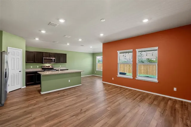 a large kitchen with stainless steel appliances granite countertop a stove and a wooden floors