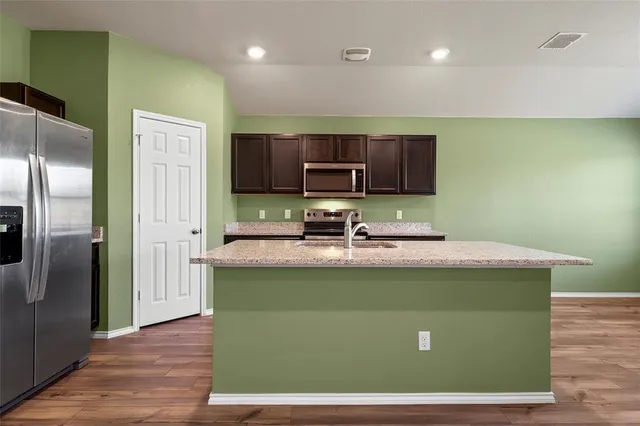a kitchen with stainless steel appliances granite countertop a sink a refrigerator and a stove