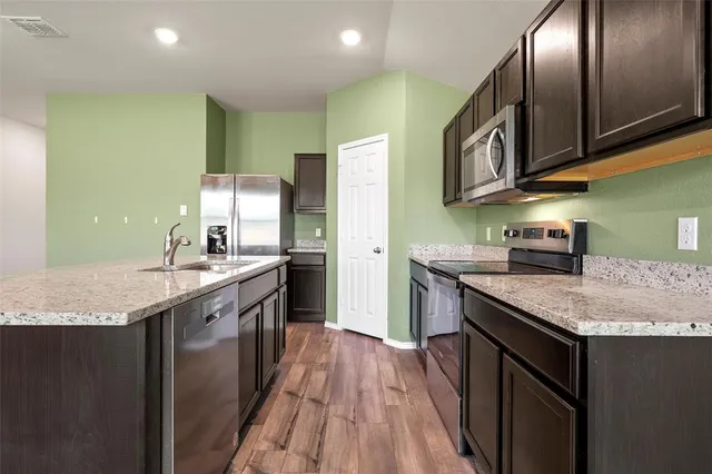 a kitchen with stainless steel appliances granite countertop a sink stove and refrigerator