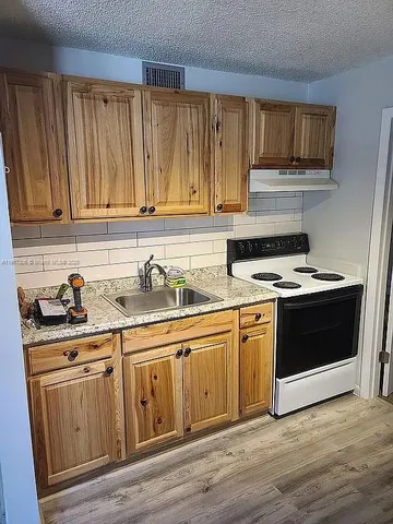a kitchen with granite countertop wooden cabinets and a stove top oven