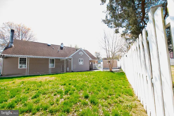 a view of a yard in front of a house with plants and large trees