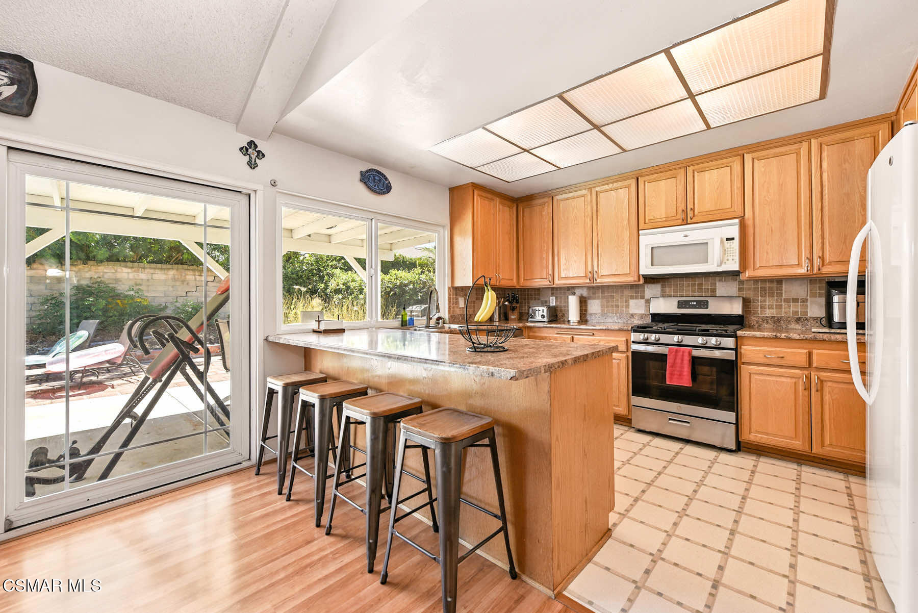 2238 Connell Avenue Simi Valley, CA 93063 - Photo 7 of 26 a kitchen with stainless steel appliances granite countertop a stove top oven a sink dishwasher a dining table and chairs with wooden floor