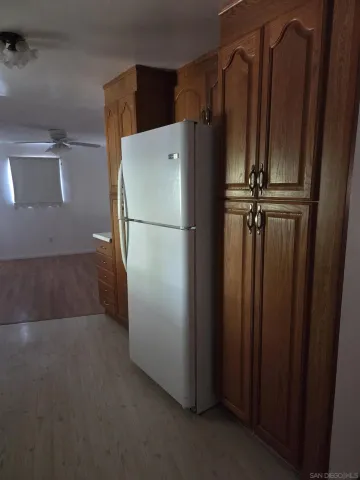 a view of a refrigerator in kitchen and white cabinets