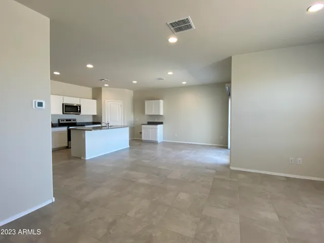 a view of kitchen with refrigerator and white cabinets