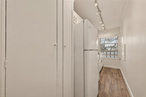 a view of a hallway with wooden floor and a cabinet
