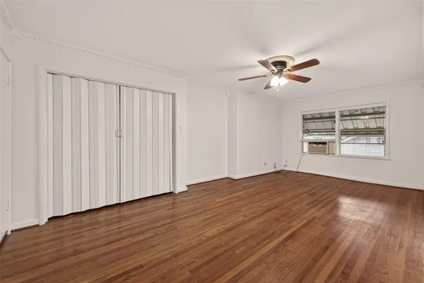 a view of empty room with wooden floor and fan