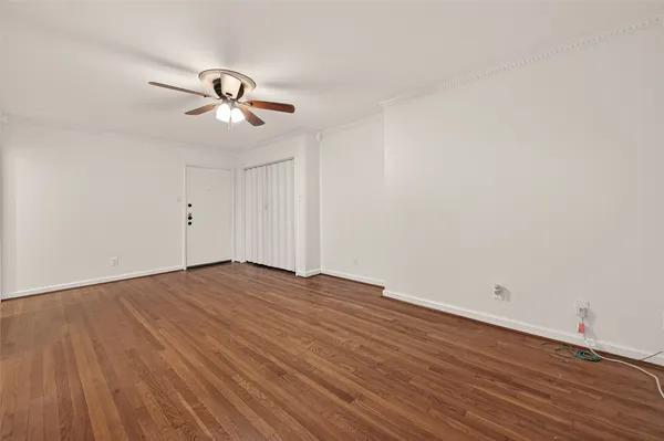 a view of empty room with wooden floor and ceiling fan