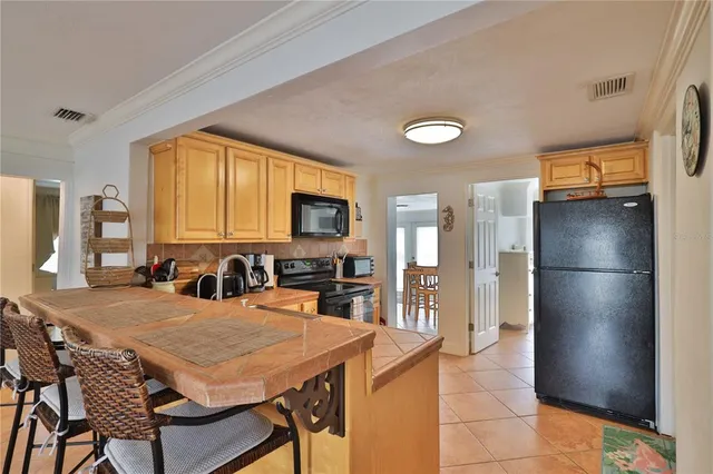 a kitchen with stainless steel appliances a refrigerator a stove a sink a dining table and chairs