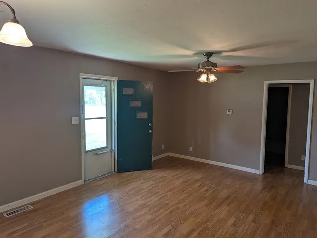 an empty room with wooden floor and windows