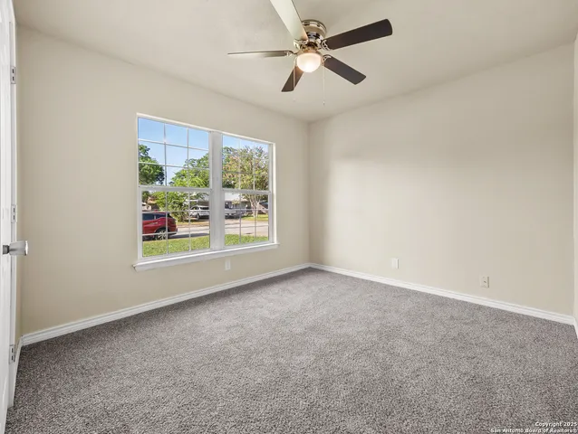 an empty room with windows and ceiling fan