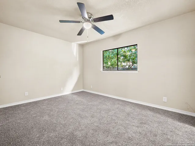 an empty room with a window and a fan
