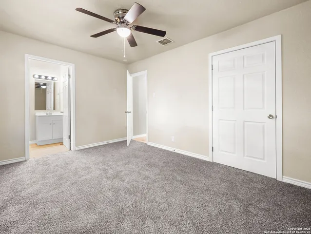 a view of an empty room and chandelier fan