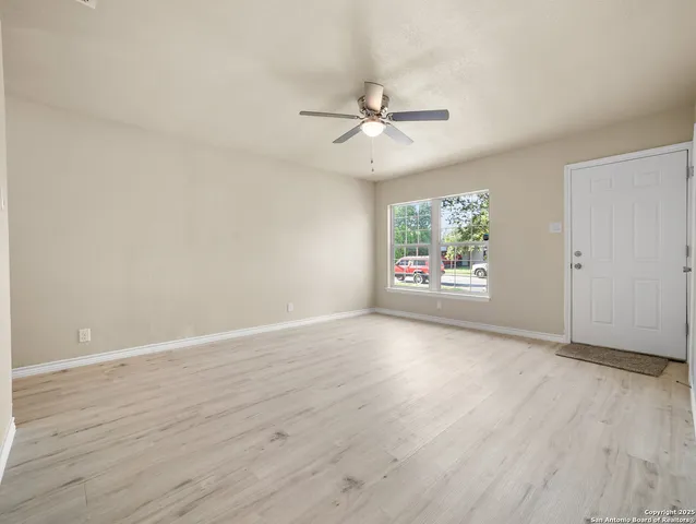an empty room with wooden floor fan and windows