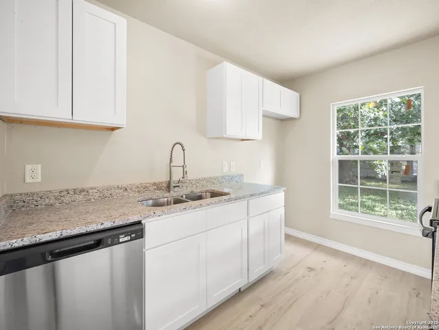 a kitchen with stainless steel appliances granite countertop a sink a stove cabinets and a window