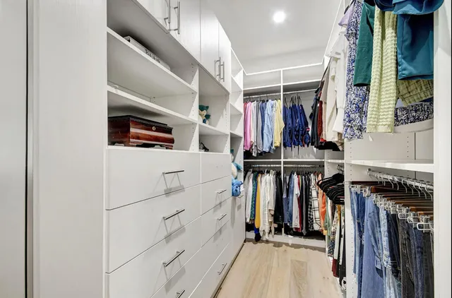 a view of walk in closet with clothes and shoes