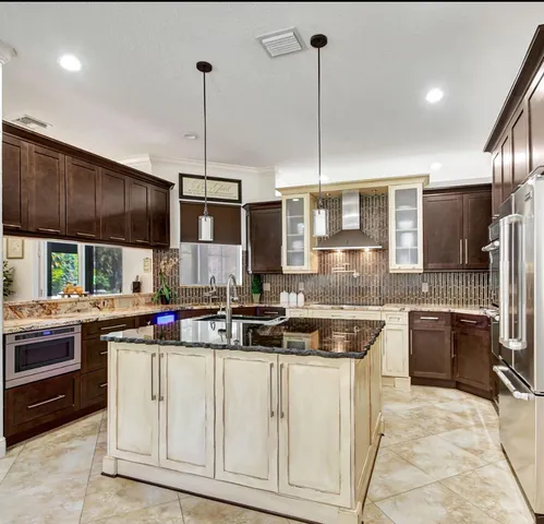 a kitchen with kitchen island granite countertop a sink a counter top space appliances and cabinets