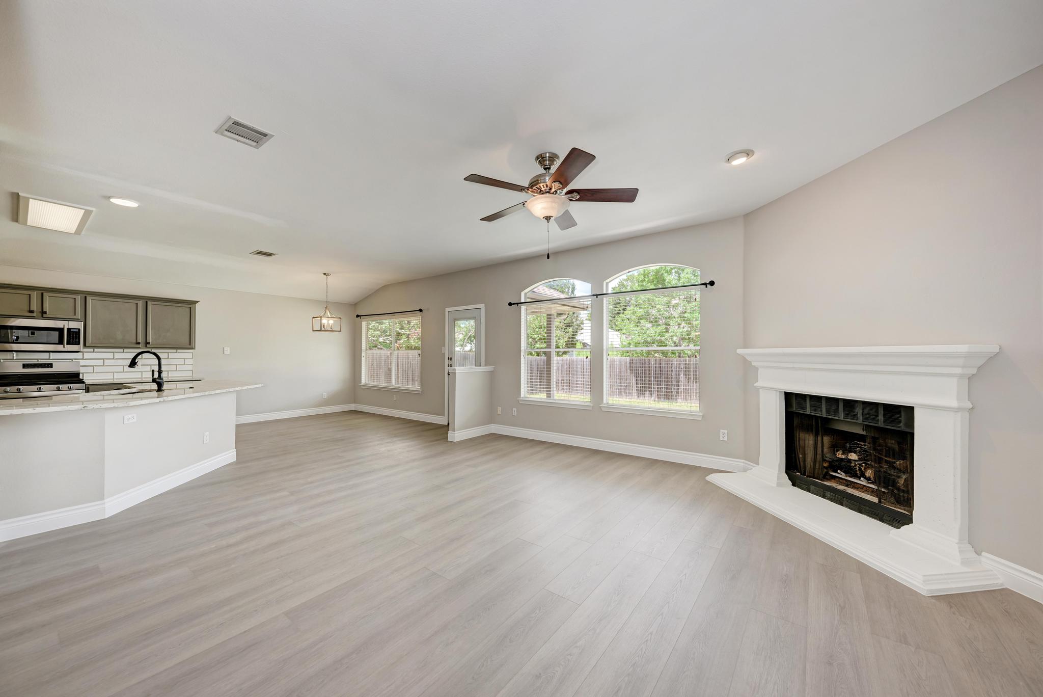 4408 Tello Path Austin, TX 78749 - Photo 8 of 38 Unfurnished living room featuring a fireplace with raised hearth, light wood-type flooring, a ceiling fan, recessed lighting, and vaulted ceiling