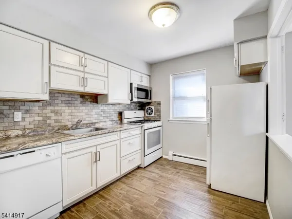 a kitchen with granite countertop white cabinets and white appliances